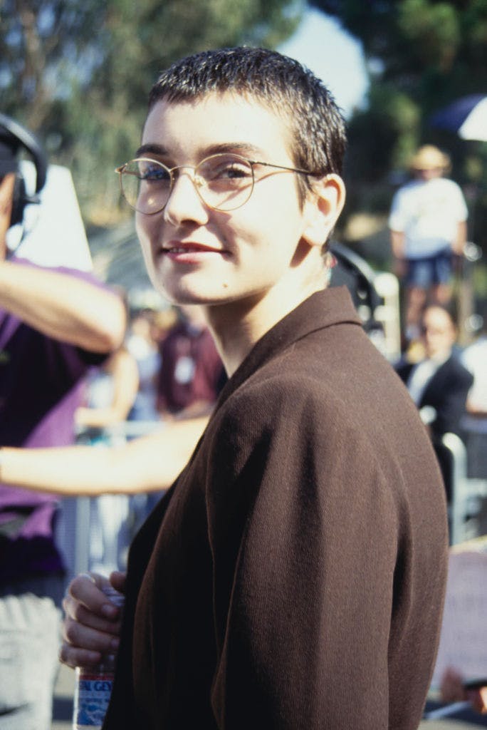 A woman in glasses and a brown jacket looking at the camera.
