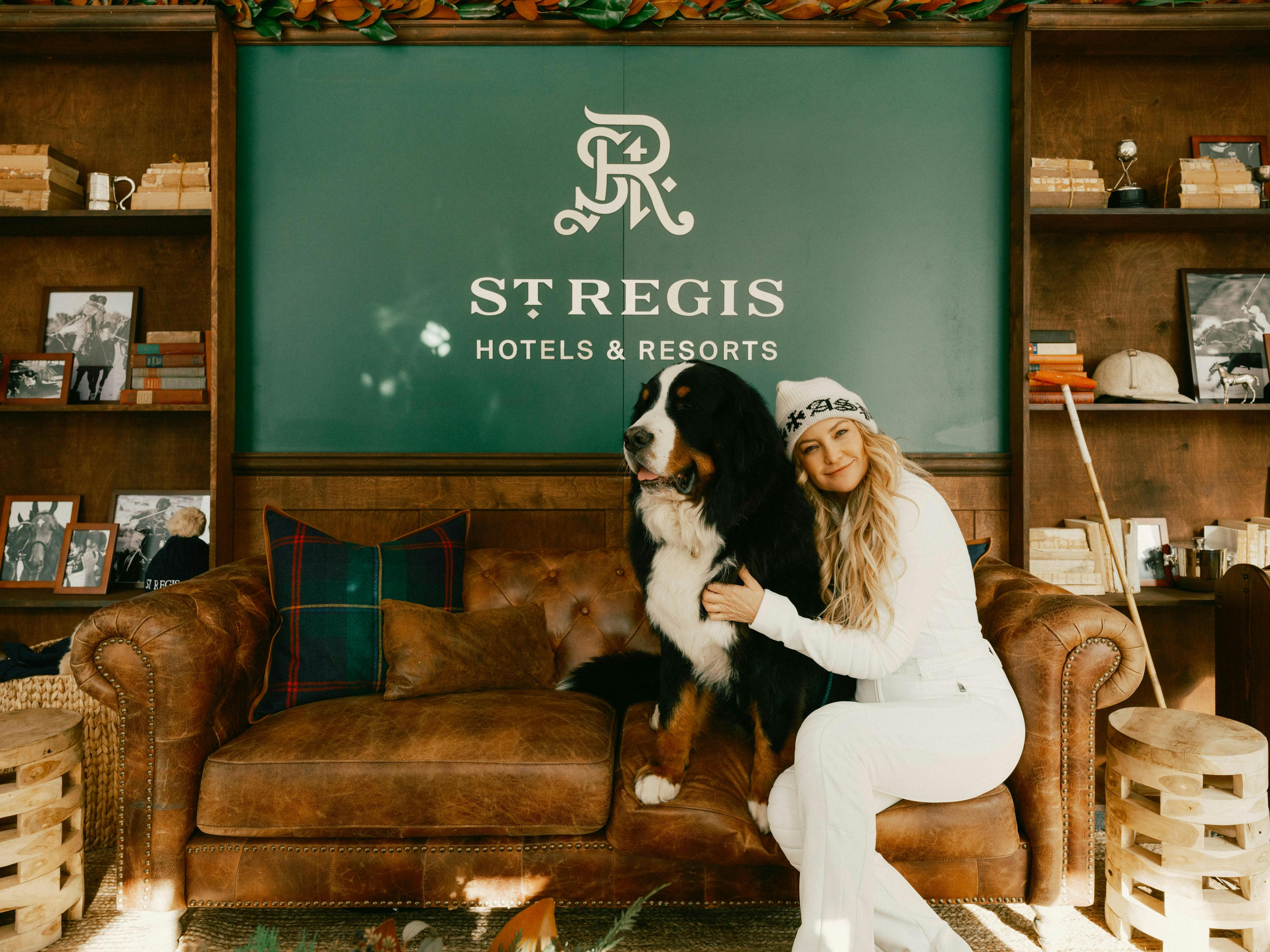 Kate Hudson on a couch with a dog green st regis sign behind her