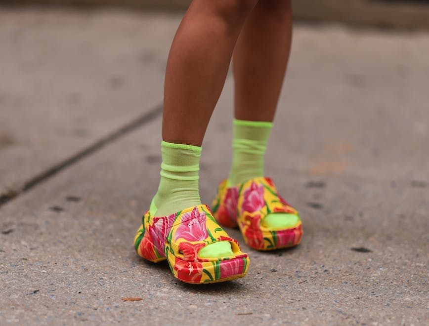 legs in colorful clogs neon green socks cement street
