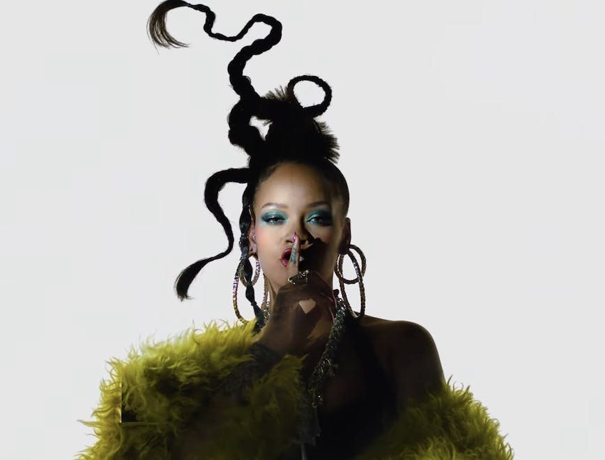 Rihanna in a yellow fur coat on a white background.