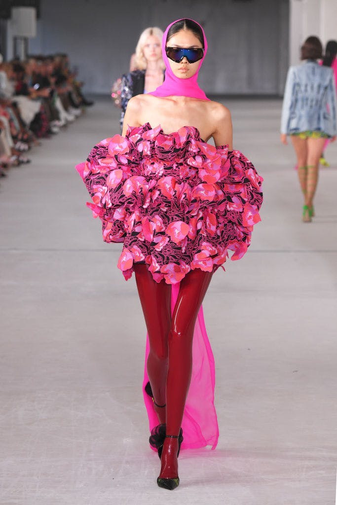 A model in a floral dress and latex red tights.