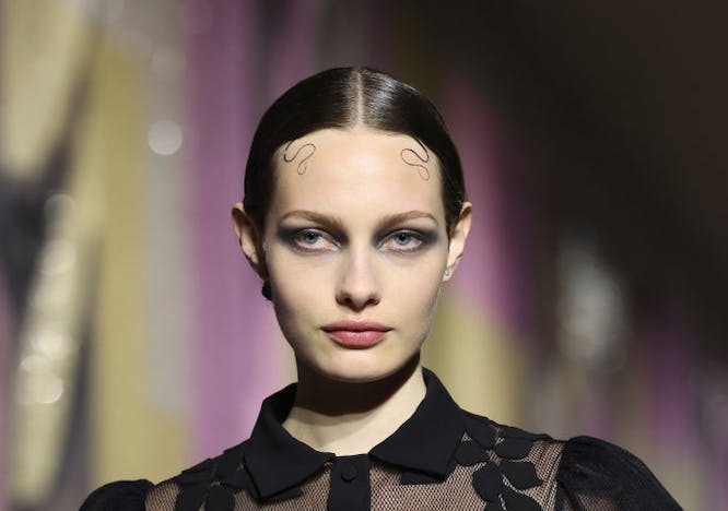 A model in slicked hair and a sheer floral top.