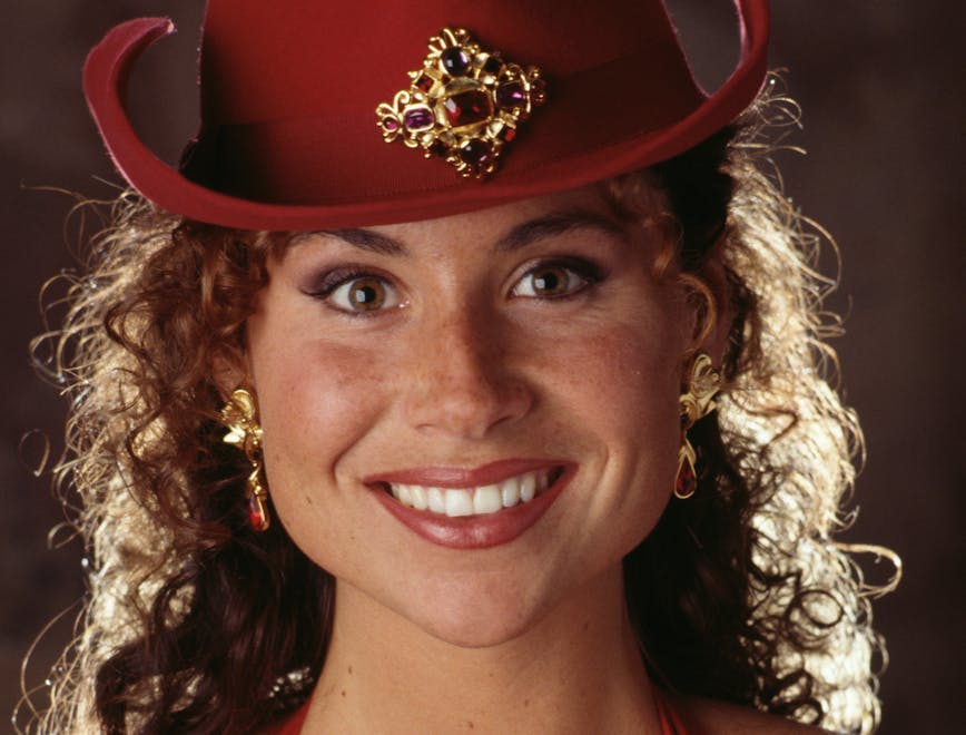 Minnie Driver wears red cowboy hat and bra with flowers on it.