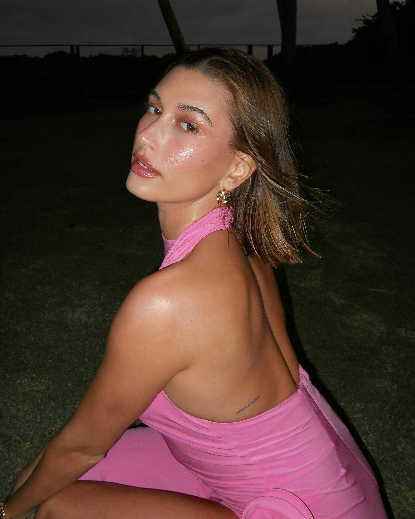 Woman in pink dress sitting on grass.