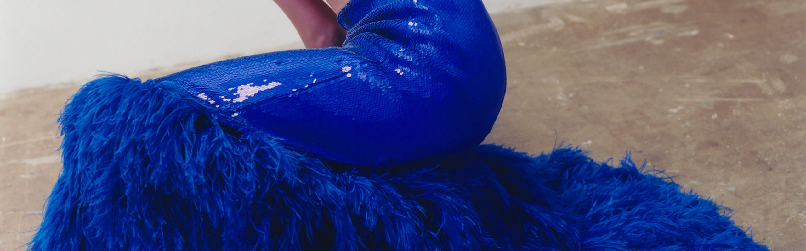 Woman wears blue feathery skirt.