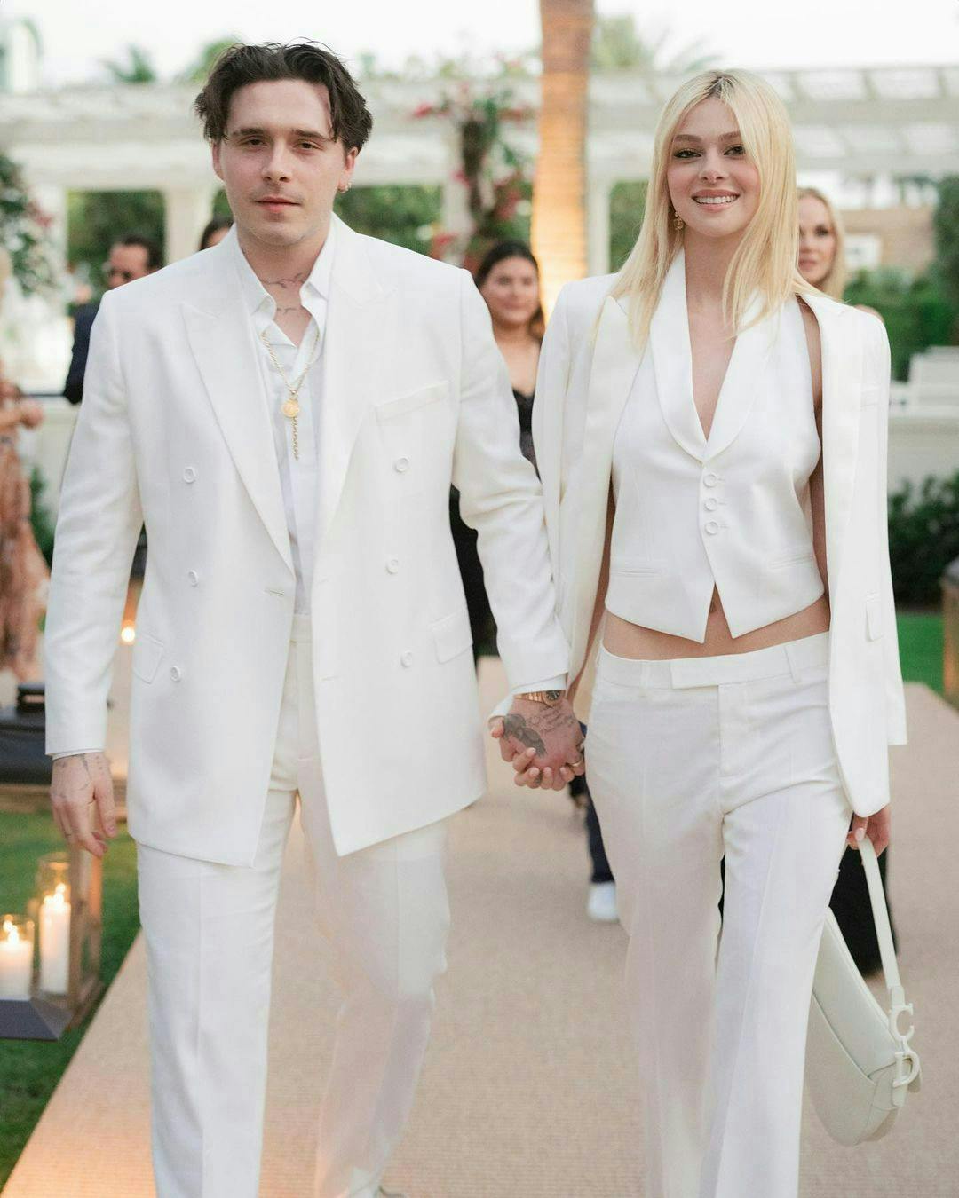 A man in a white suit next to a woman in a white vest and pants.