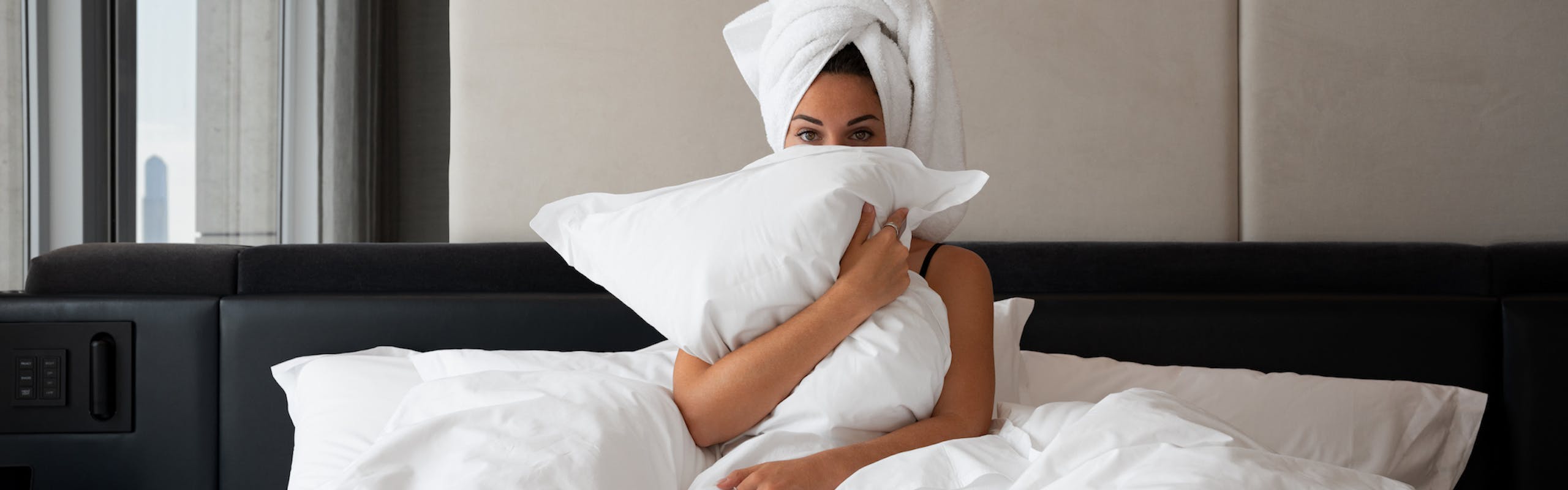 woman in bed white blanket holding a white pillow