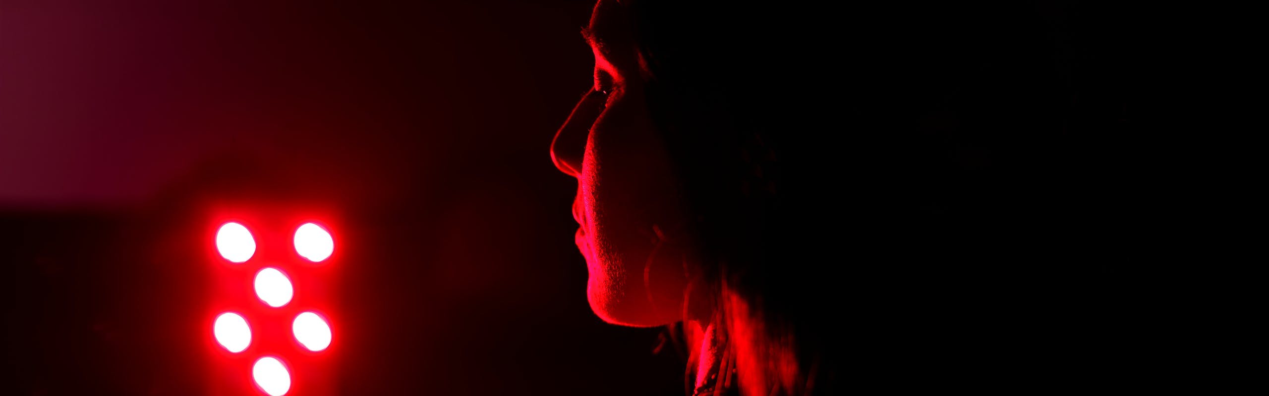 Woman standing in front of red light.