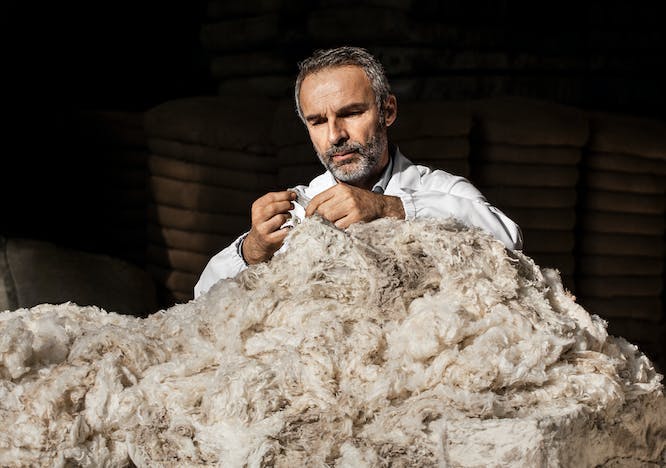 Man sewing pile of wool.