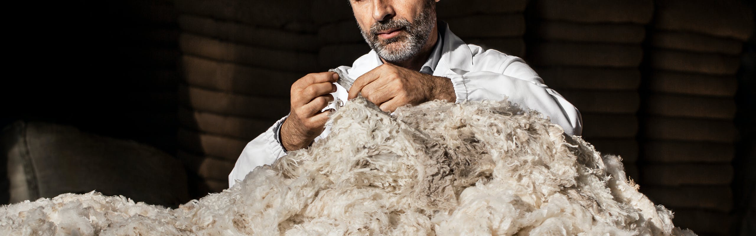 Man sewing pile of wool.