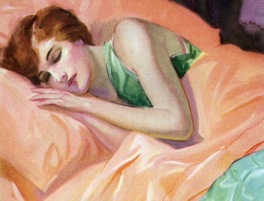 Woman wears green top and sleeps on peach colored sheets.