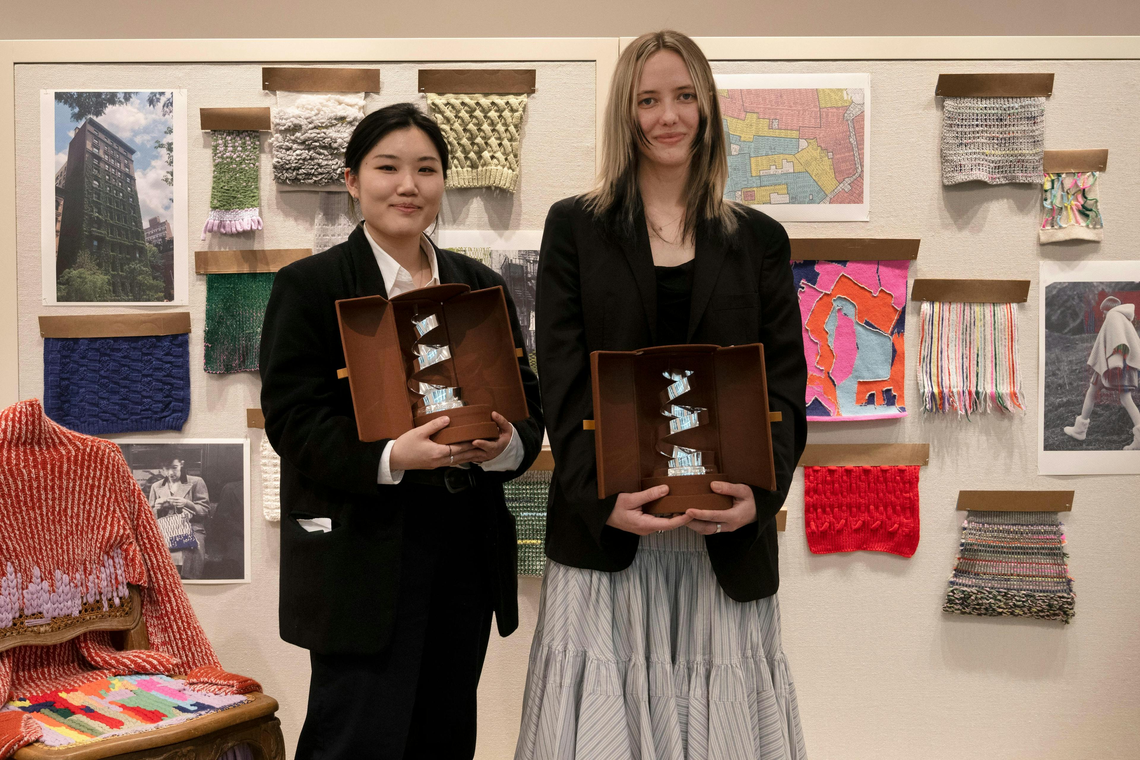 Two student designers holding trophies for the camera.