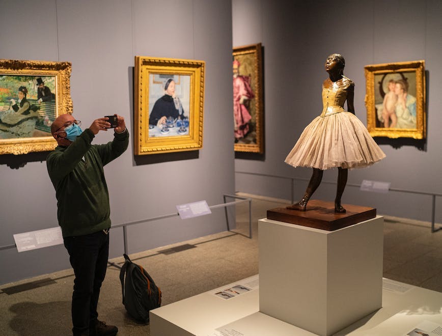 Man taking a picture of Degas' "The Little Dancer" at The Metropolitan Museum in NYC.