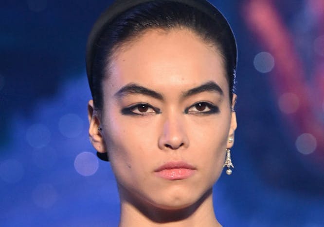A model with dark eyeliner and a black top.