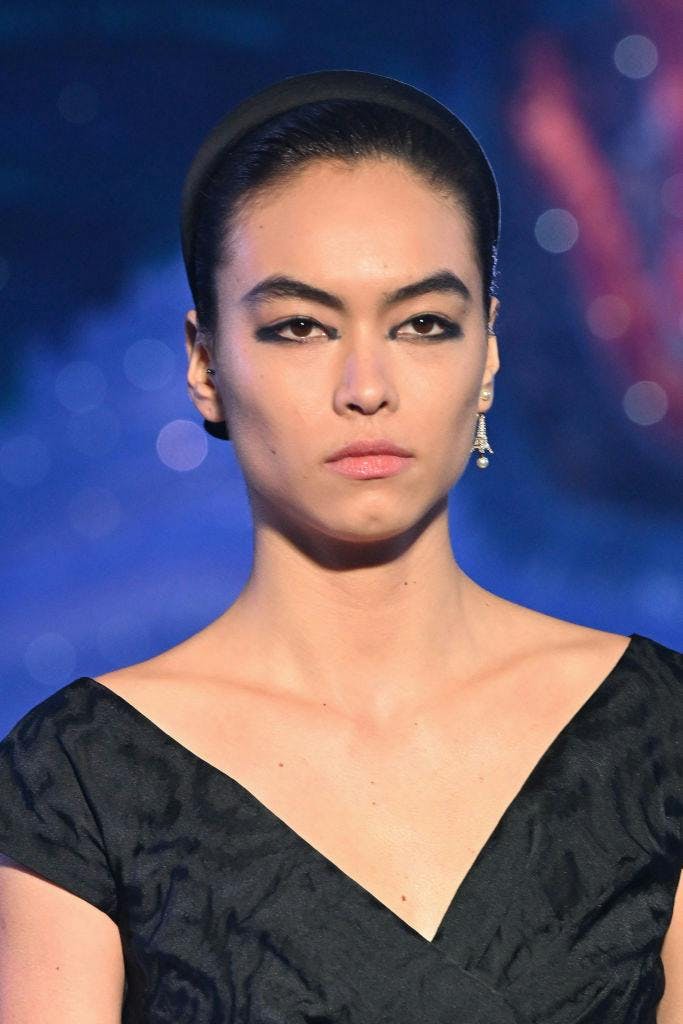 A model with dark eyeliner and a black top.