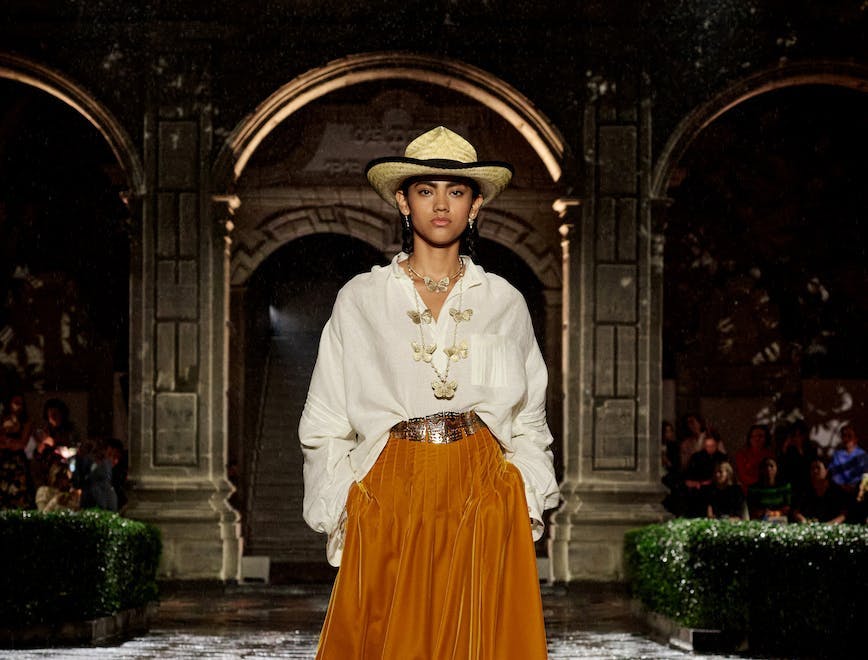 A model walking in a white shirt and orange skirt.