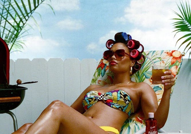A model with hair rollers and wearing a bikini while lounging.