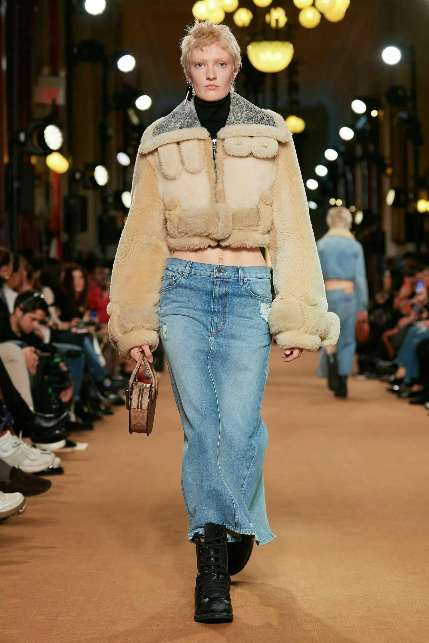 A model in a shearling jacket and denim maxi skirt.