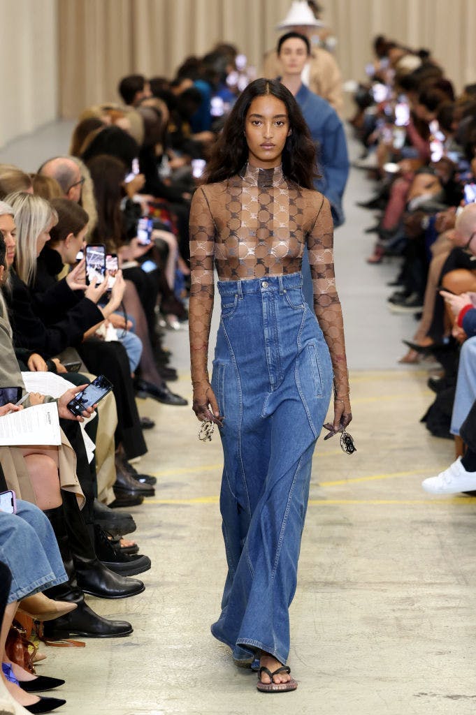 A model in a mesh top and denim skirt.