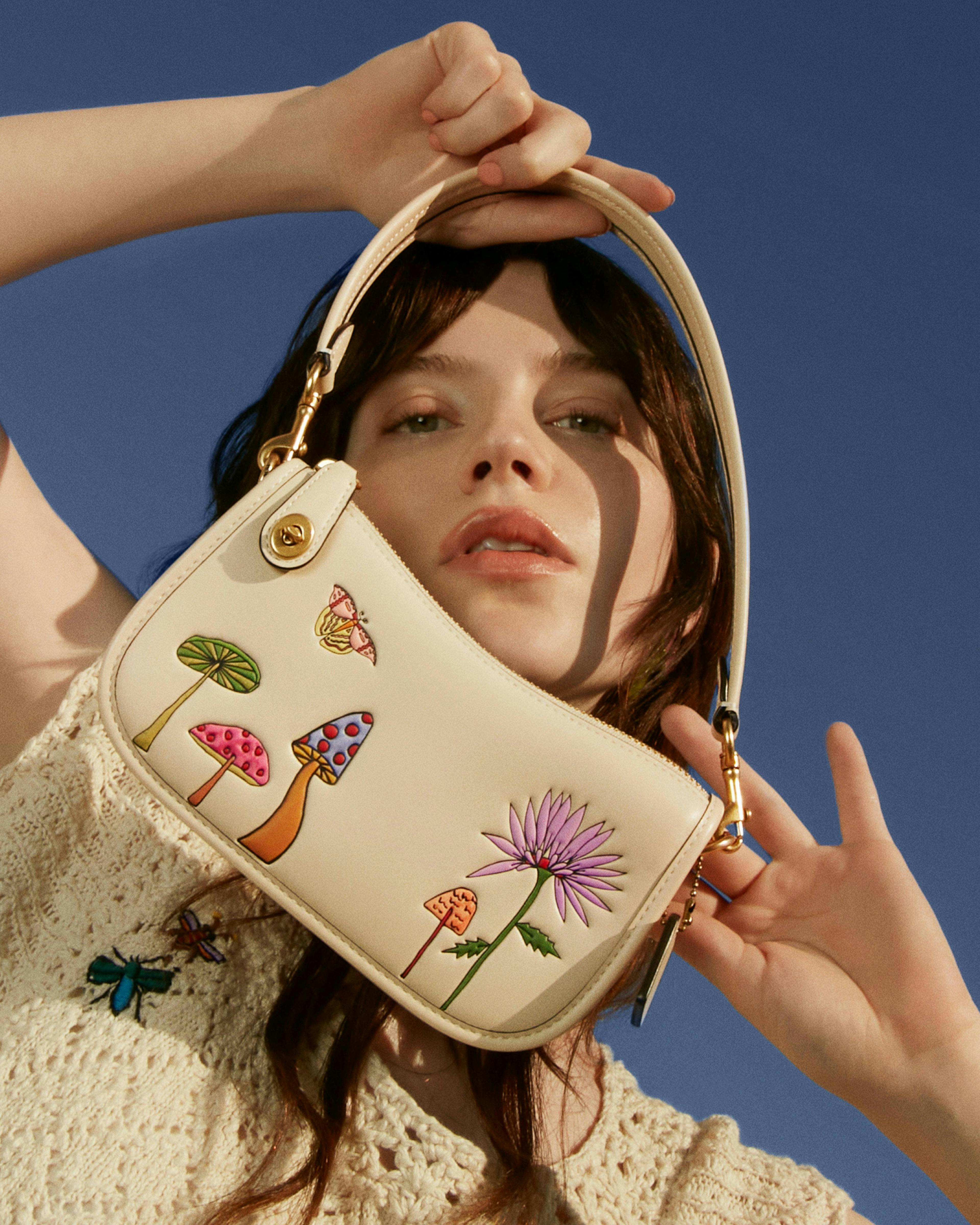 A model holding a bag from Coach observed by us collection with Kirsten dunst