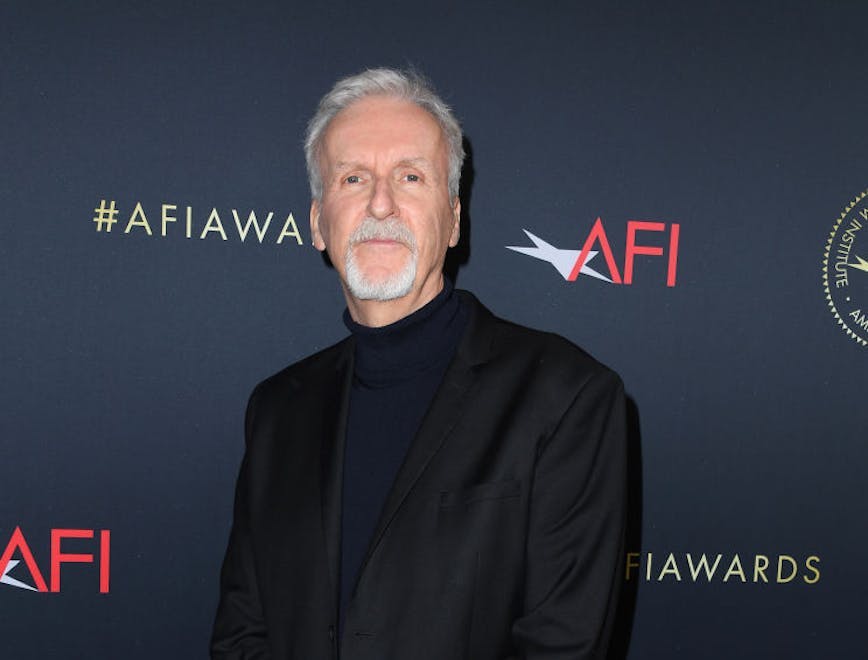 james cameron net worth standing in a black suit