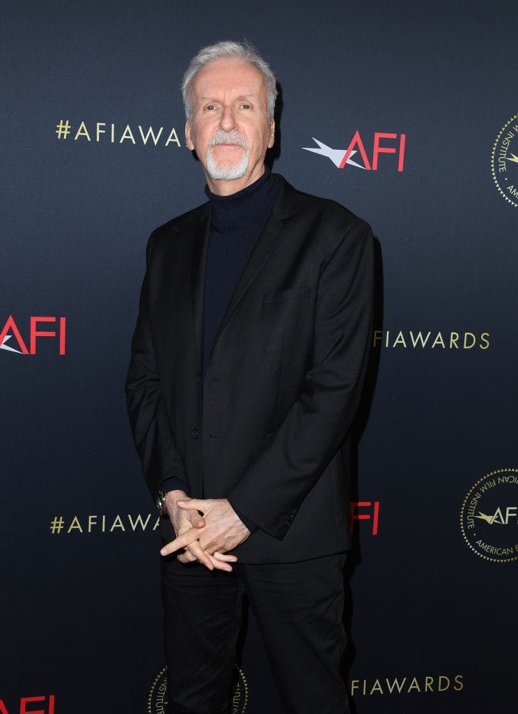 james cameron net worth standing in a black suit