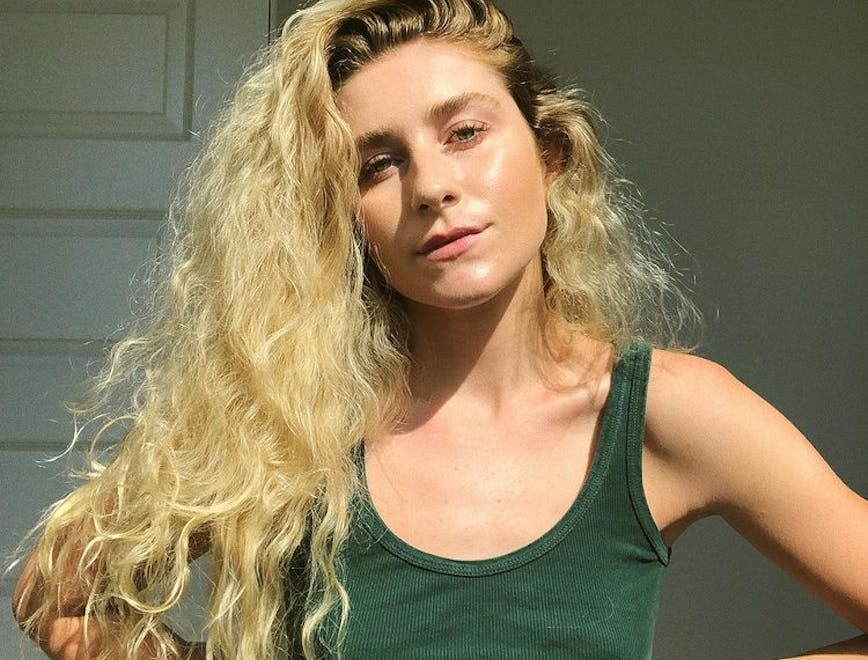 Courtney Taylor Olsen wearing a green tank top and her hair swept to the side.