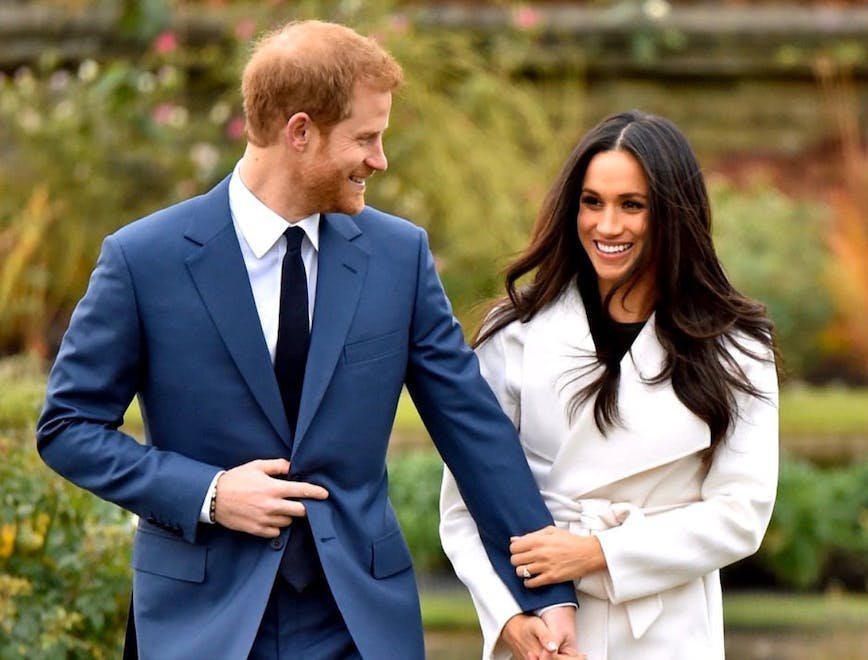 Meghan Markle in white coat and Prince Harry in blue suit