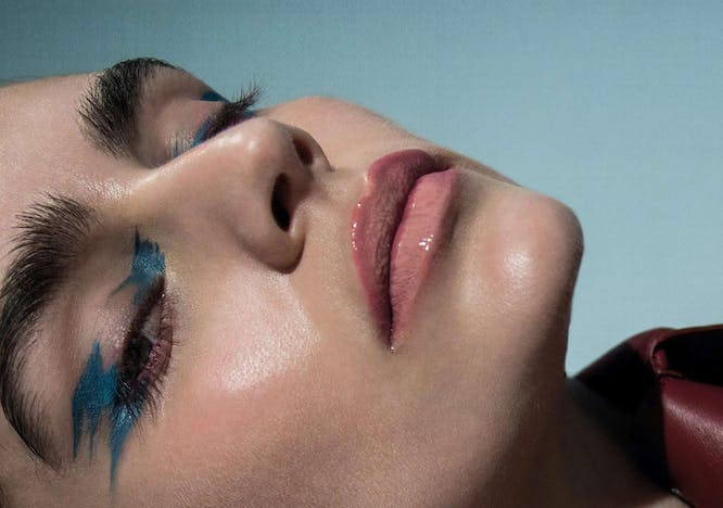 A model in blue eyeliner and nude lipgloss.