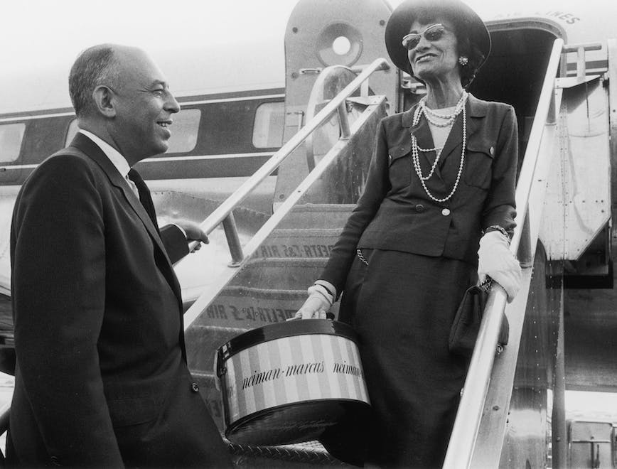 Chanel family brand history; Coco Chanel boarding a plane after the opening of a new Neiman-Marcus store.