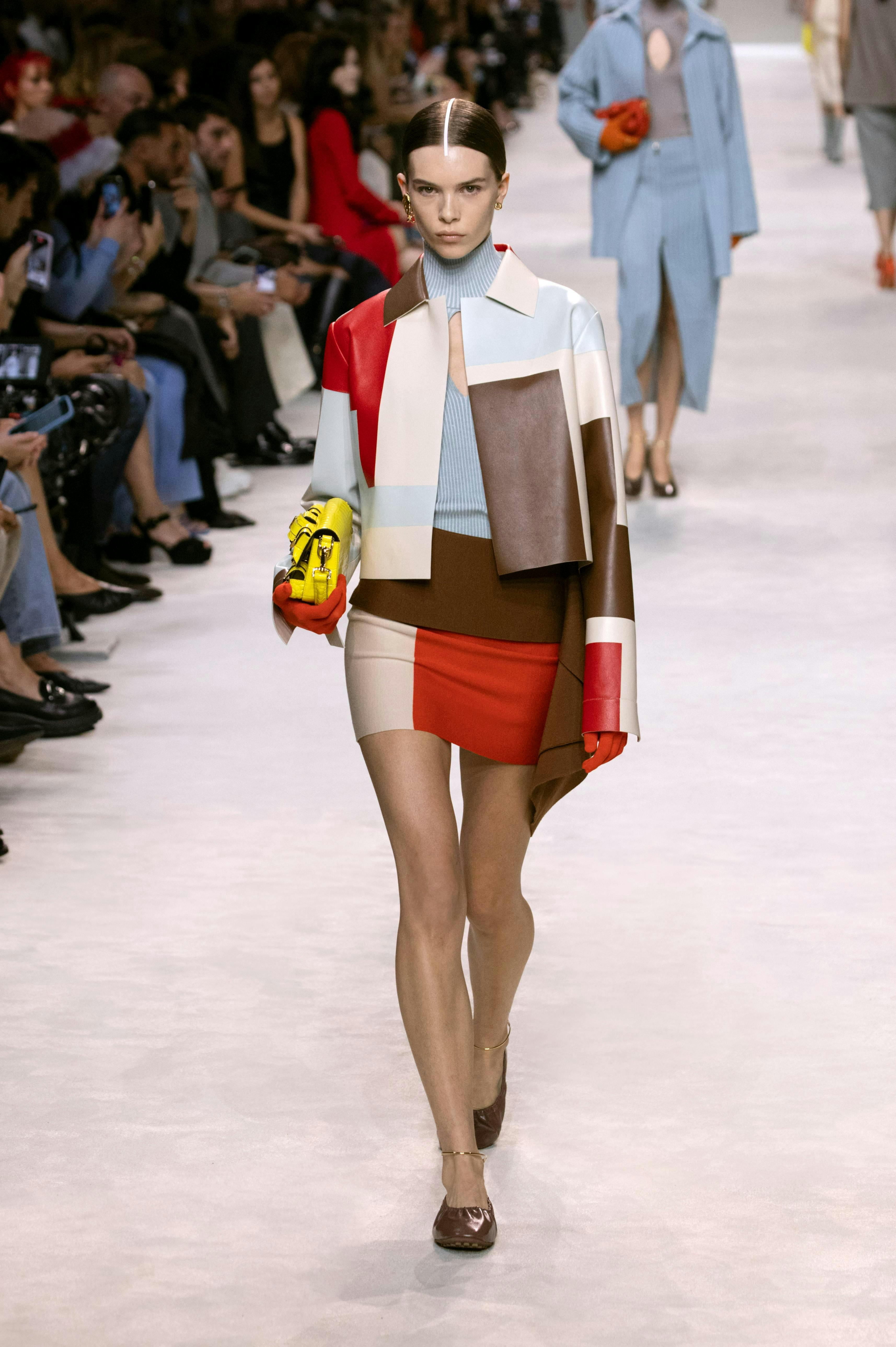 model in colorblocked jacket, blue top, and mini skirt