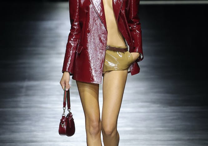 model in red patent leather jacket and mini shorts