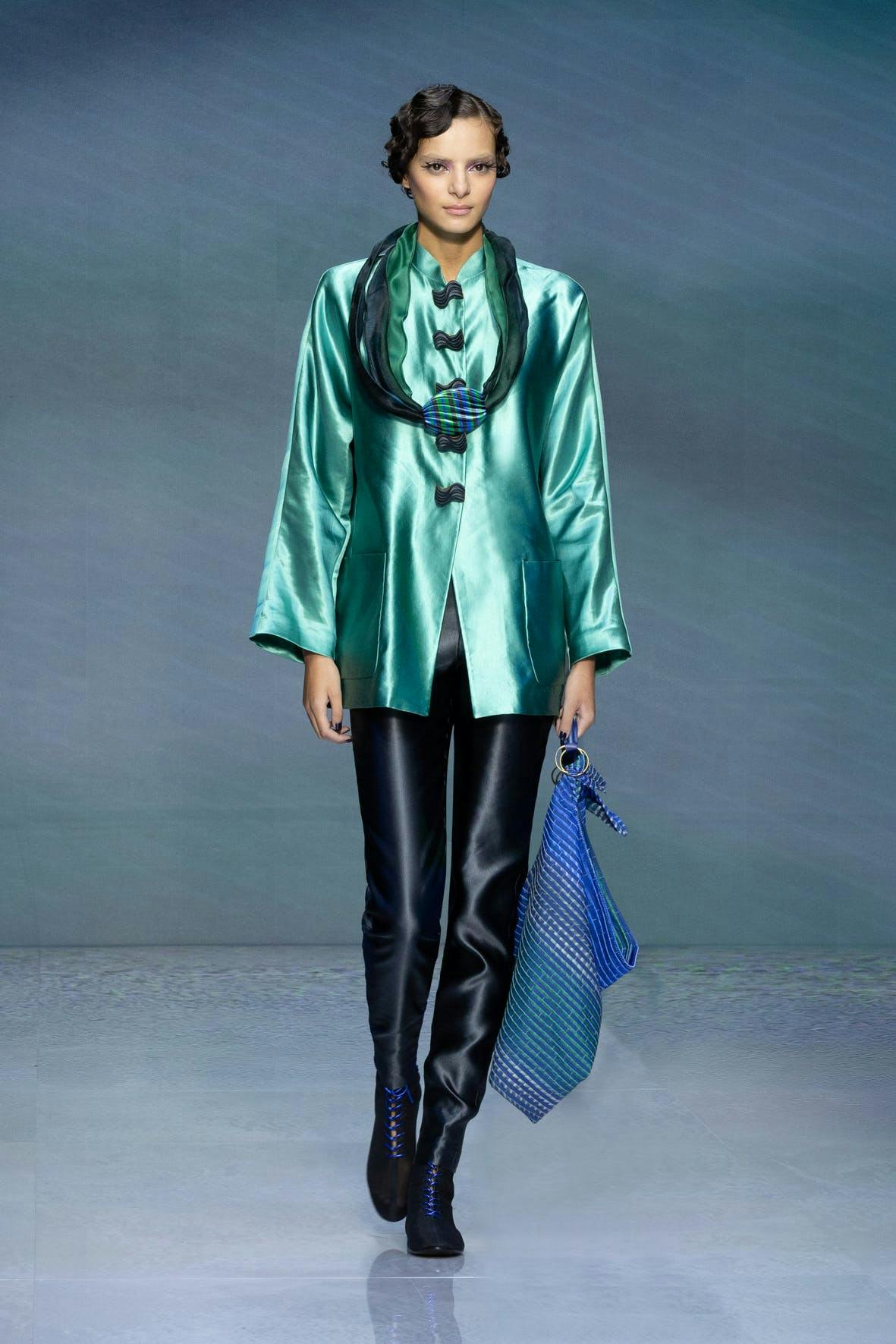 model in irridescent green jacket and black trousers