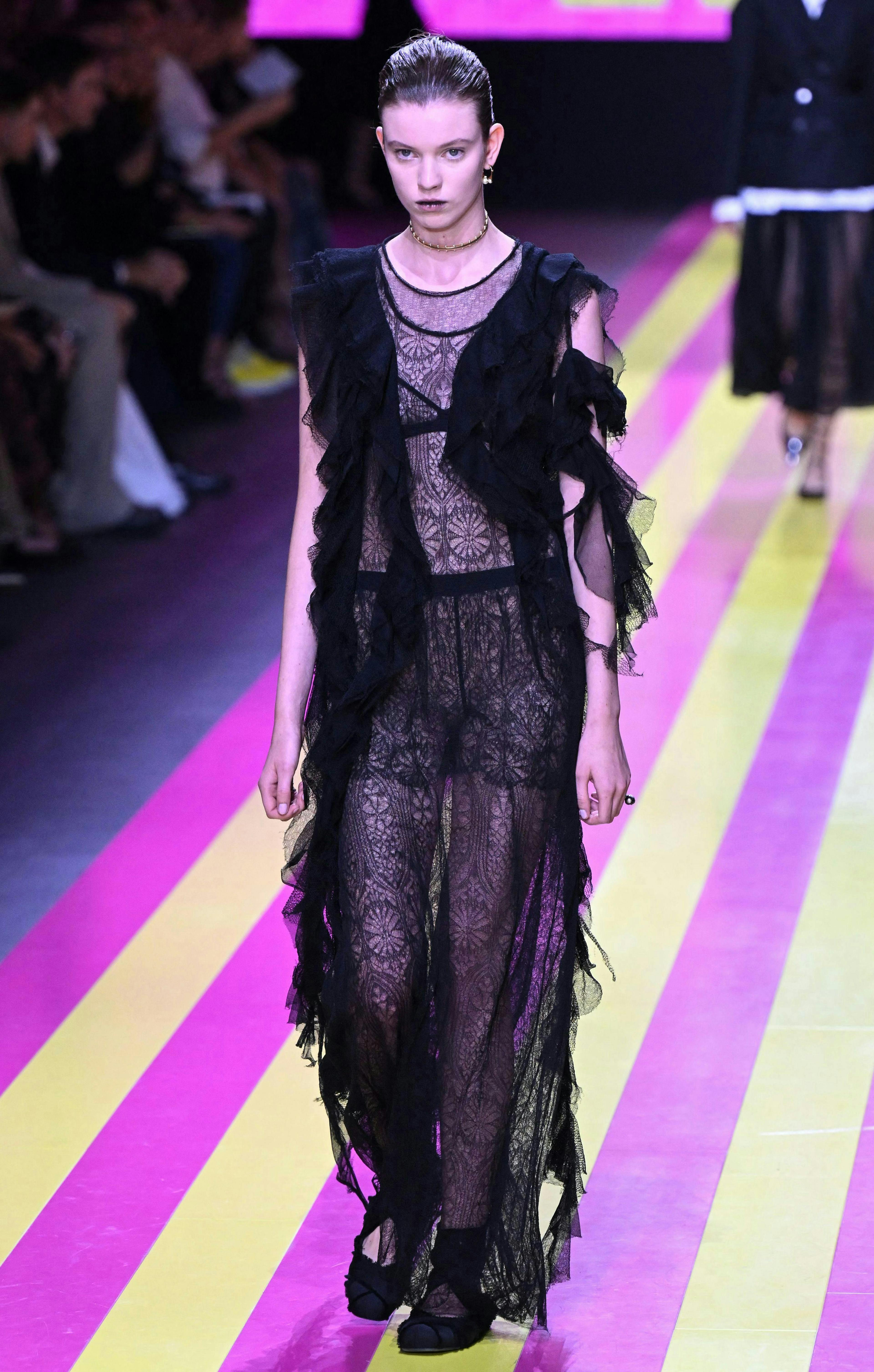 model in black lace dress with ruffled overlay