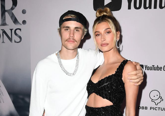 justin bieber, wearing white shirt and pink pants, with hailey bieber, wearing black dress