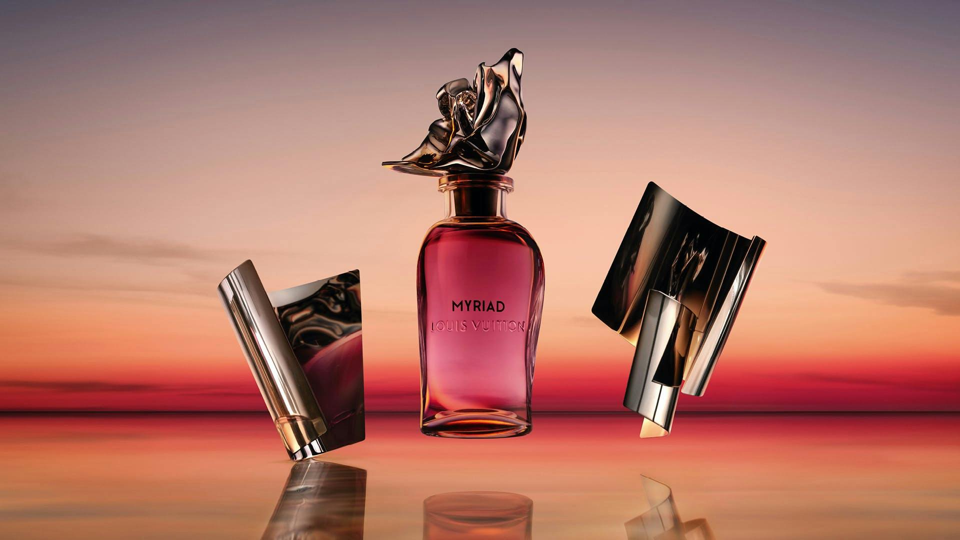 a pink bottle of perfume against an orange sunset backdrop