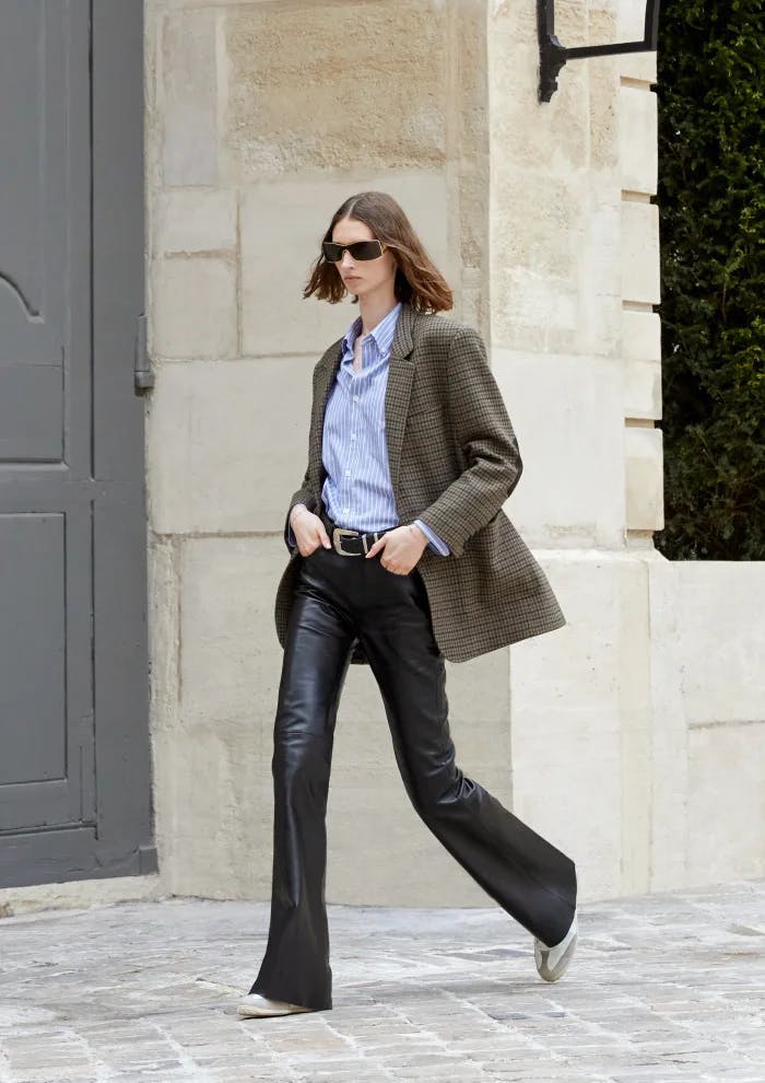a model in a blazer, blue button down, and leather pants