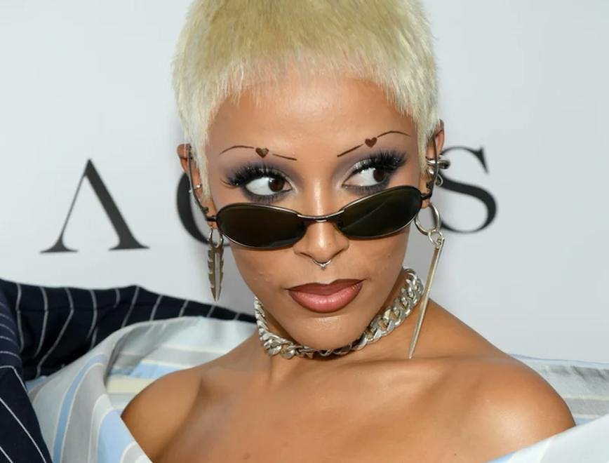 doja cat with pinstripe top, black sunglasses, and heart eyebrows