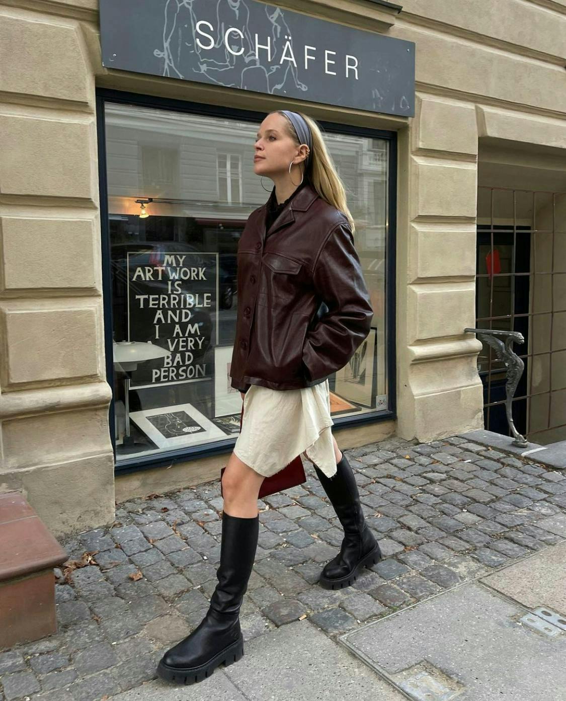 woman wearing leather jacket and skirt walking down street