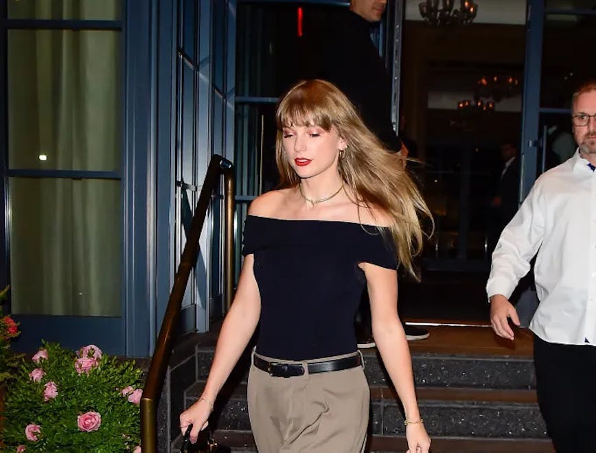 taylor swift outfits; taylor swift in black off the shoulder top and brown pants