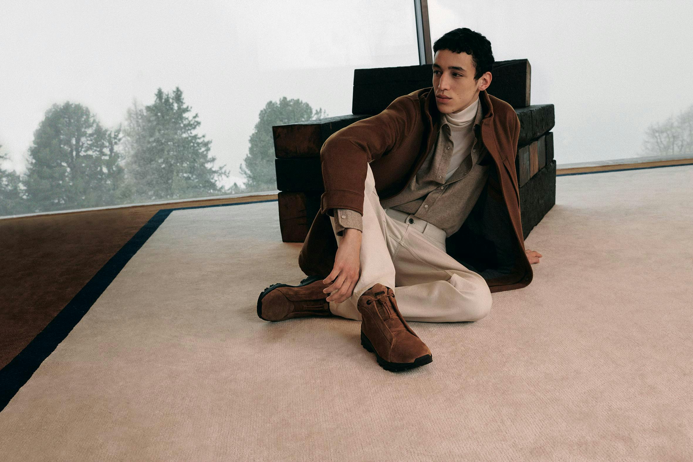 a model in a brown coat, tan pants, and zegan's triple stitch vetta shoes