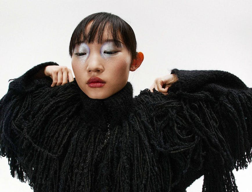 a model in a black fringe coat and wearing silver eyeshadow