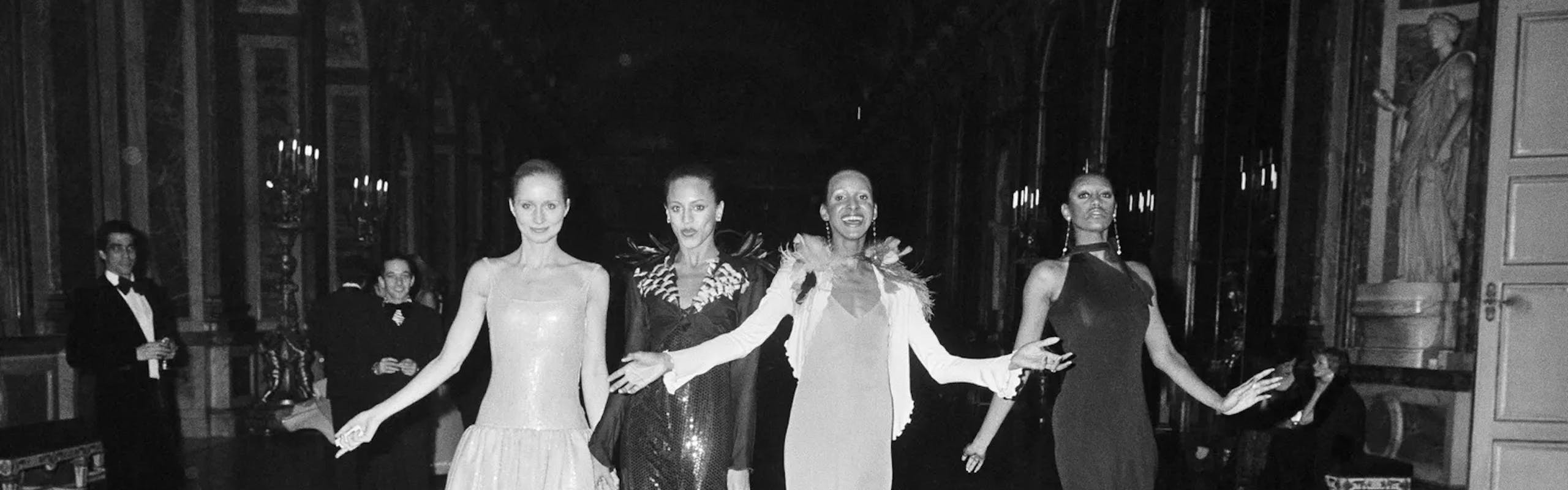 black and white photo of four models wearings designs from the show