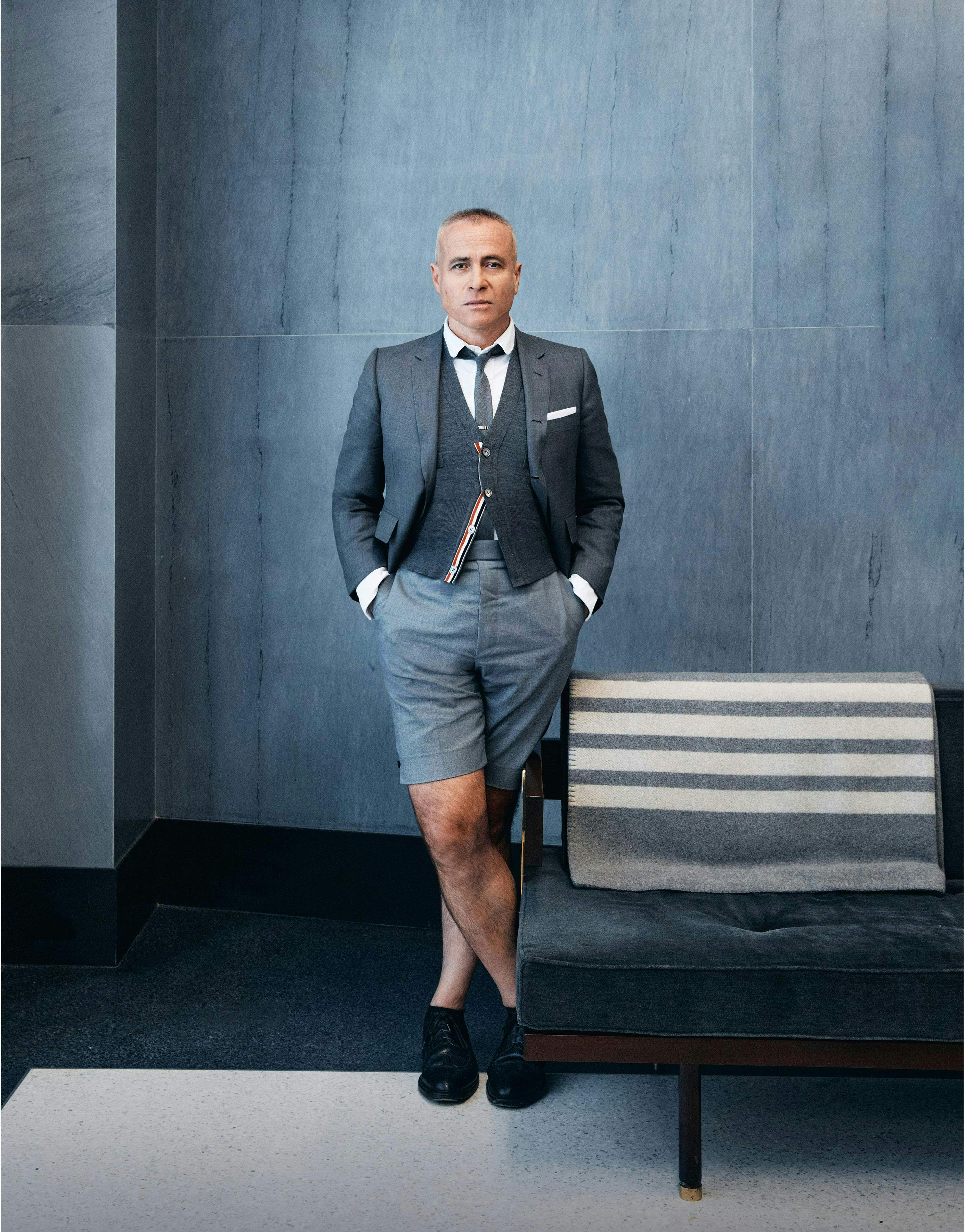 Thom Browne standing in a gray suit  top and shorts