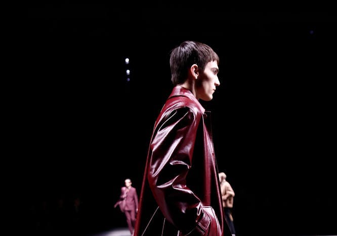 model on runway wearing red leather trench coat