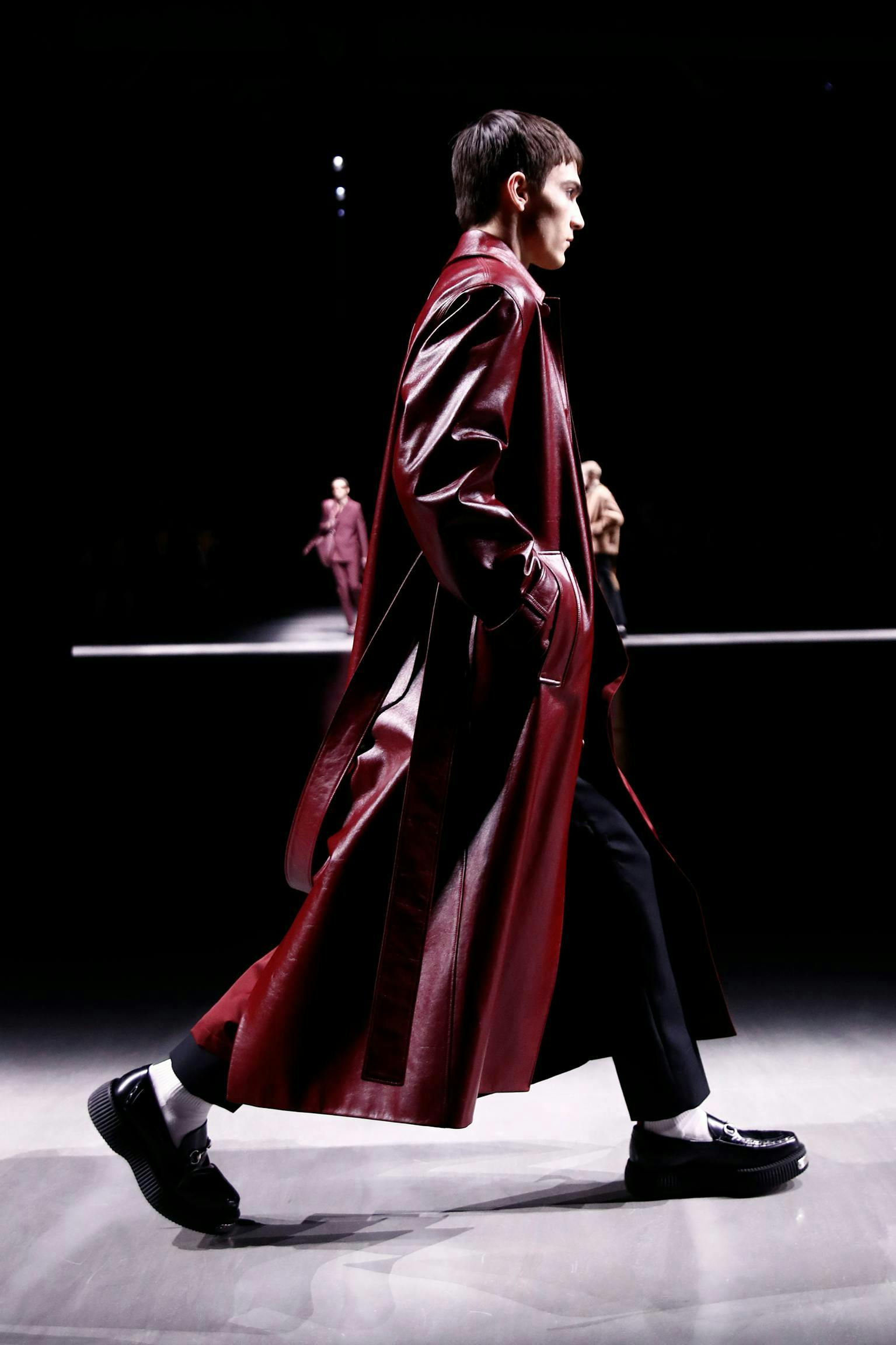 model on runway wearing red leather trench coat