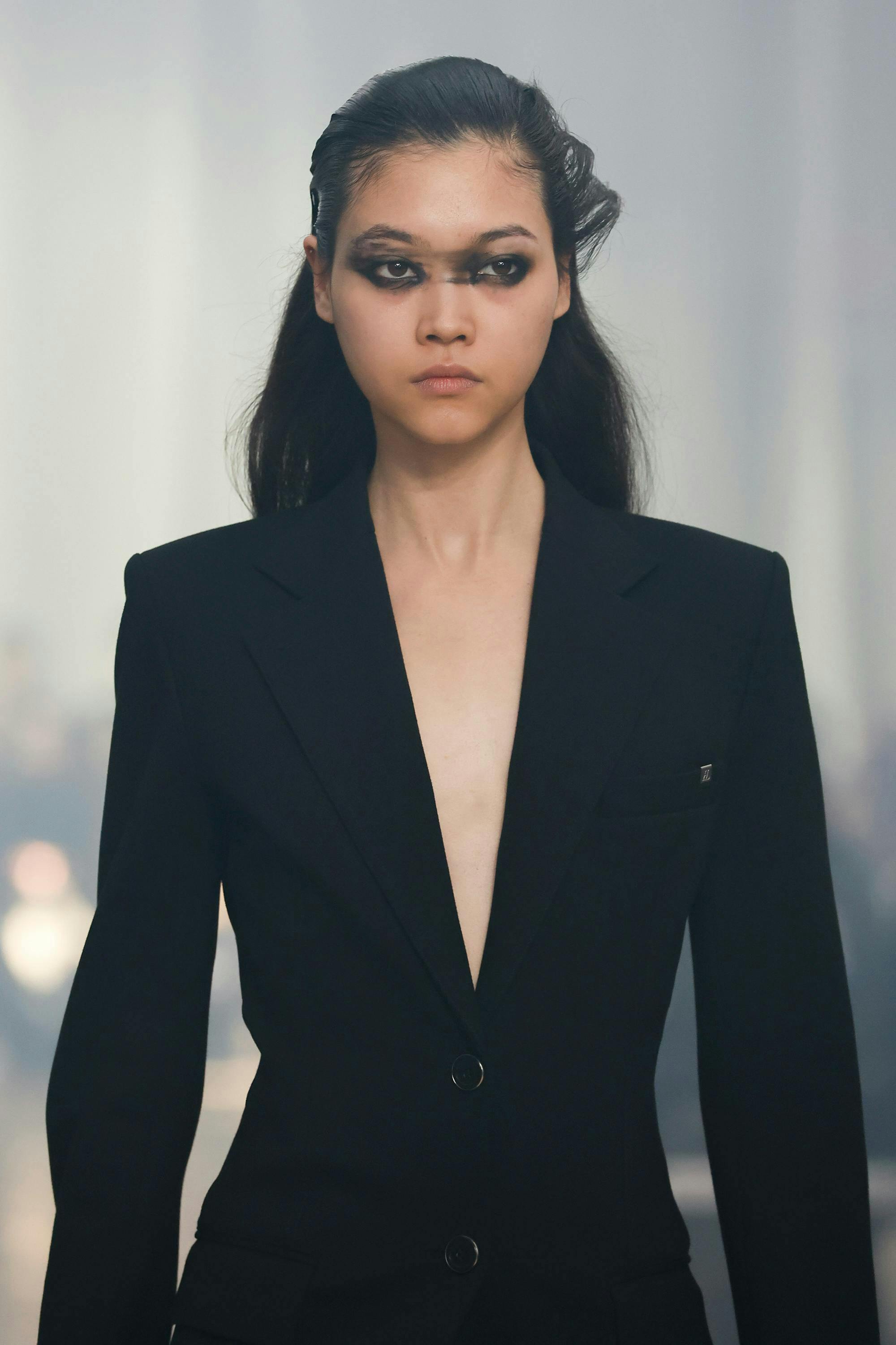 model on runway wearing black blazer with smudged makeup