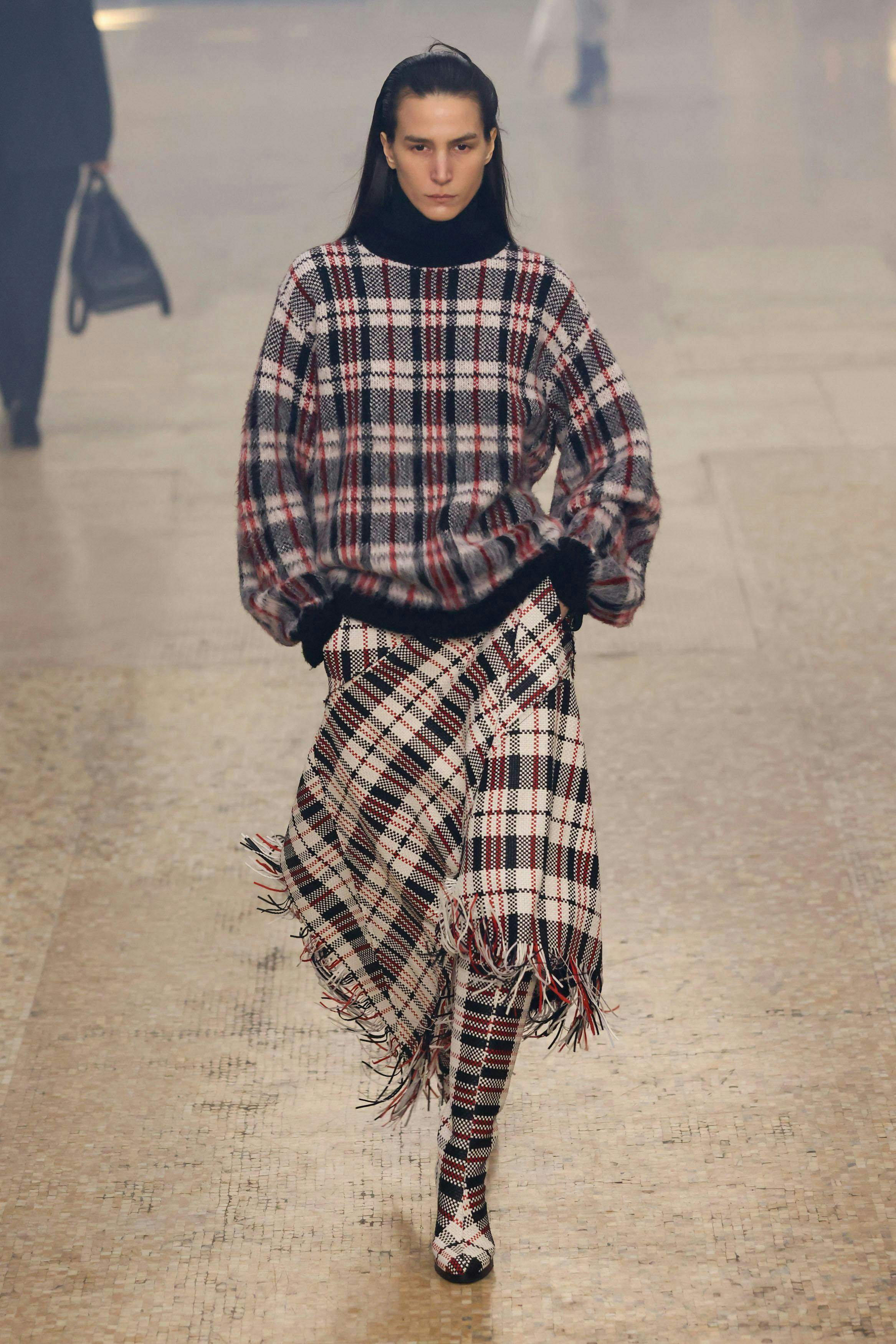 model on runway wearing plaid sweater and scarf