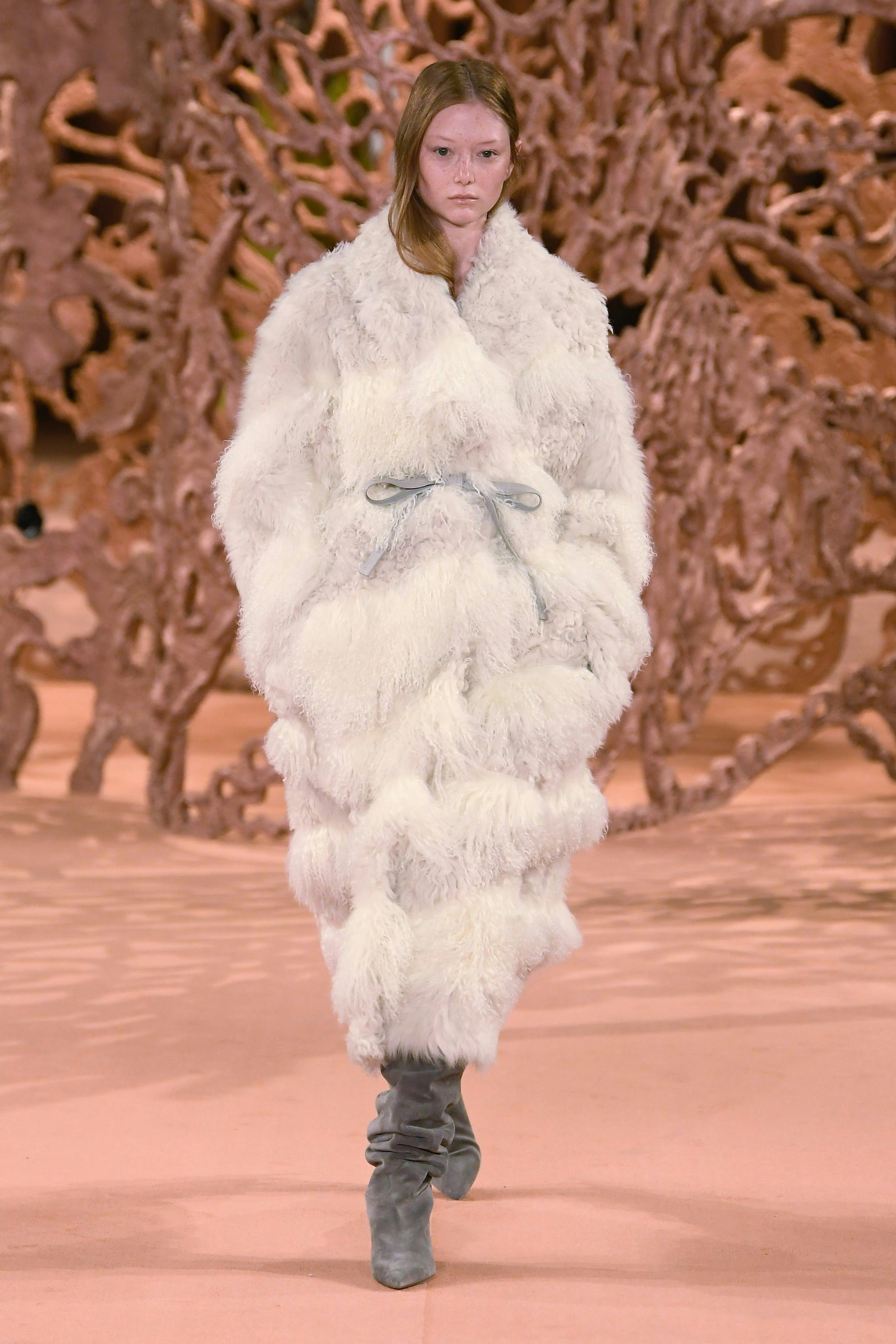 model on runway wearing oversized white coat