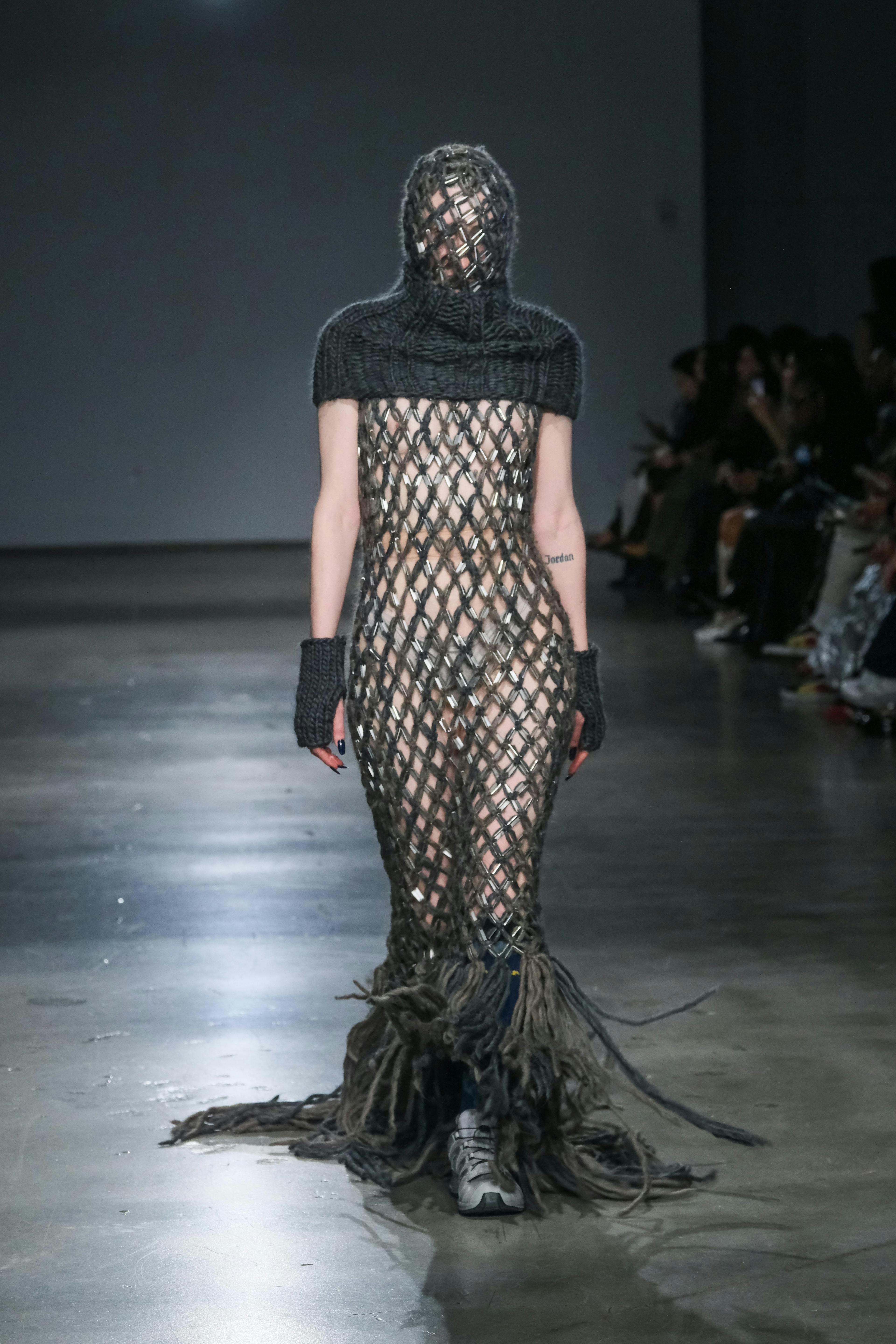 model on runway wearing mesh dress with gray knit shawl
